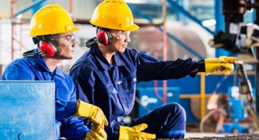 Worker in Asian factory at industrial metal cutting torch machine